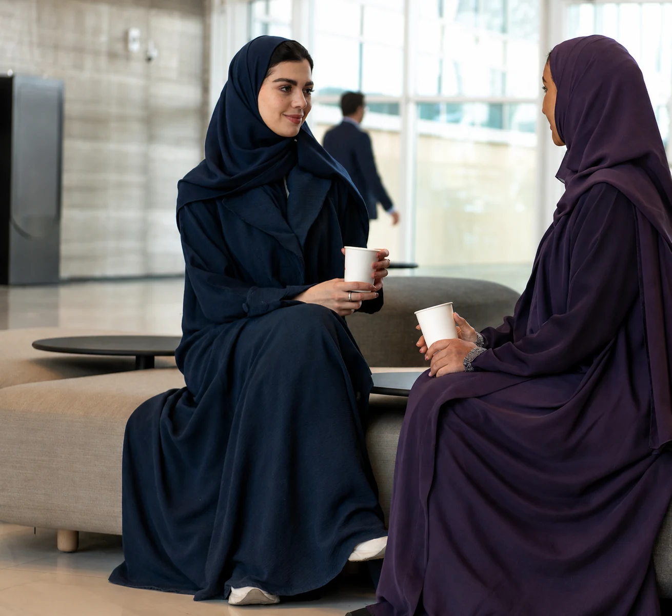 Two Saudi women professionals in discussion in a business lounge