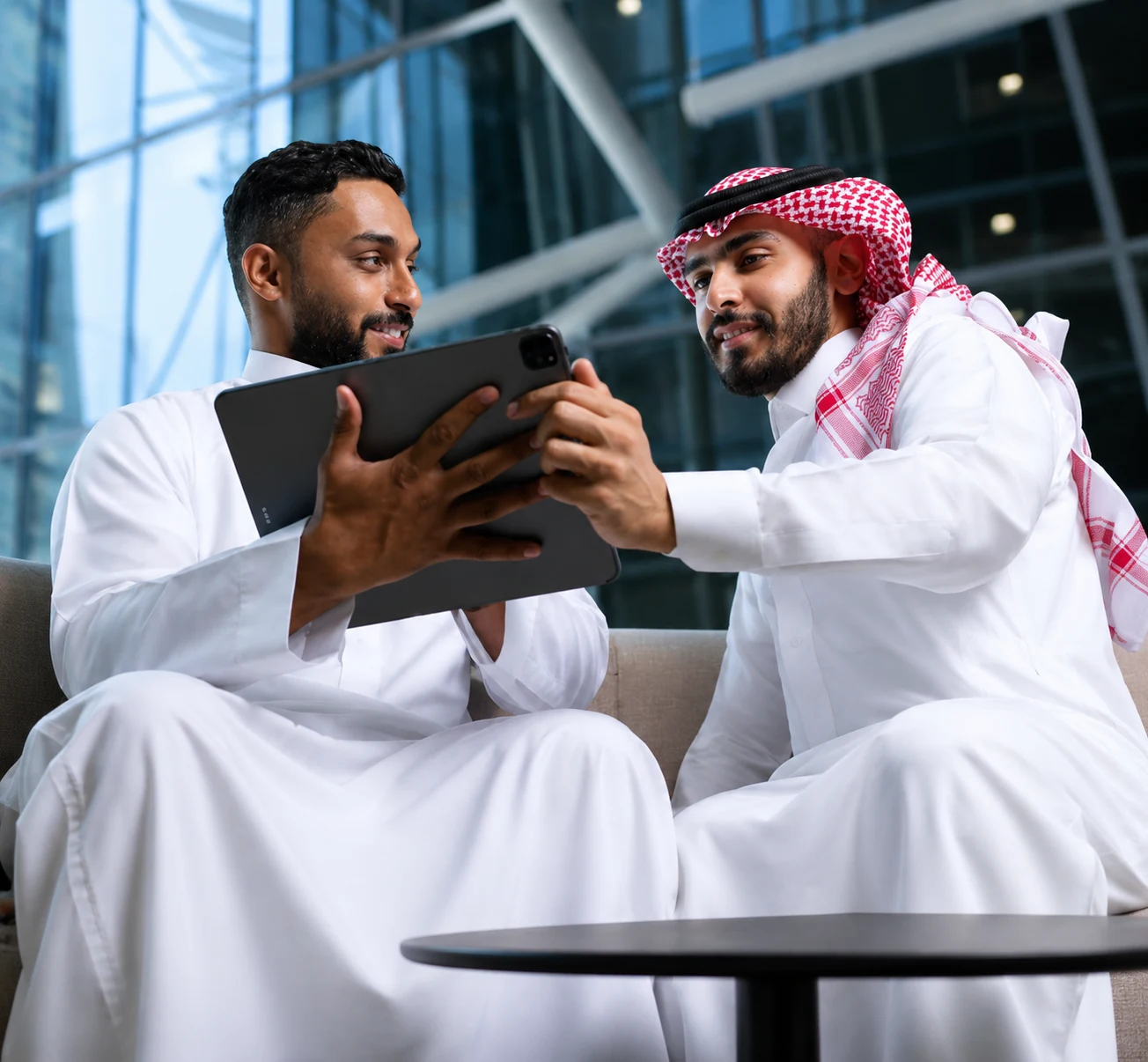 Two Saudi professionals reviewing a digital platform together on a tablet