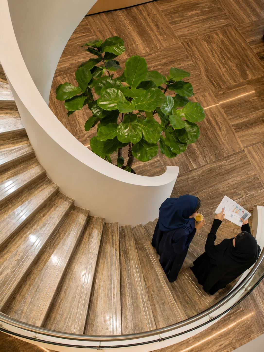Overhead view of two Saudi professionals reviewing work on an architectural staircase