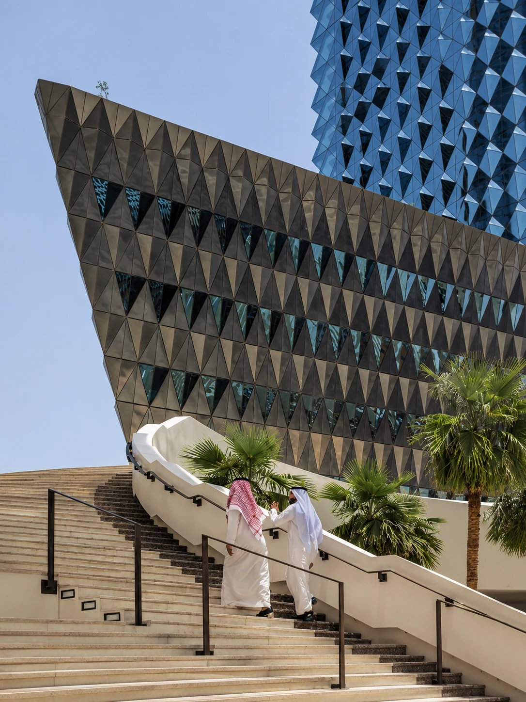 Saudi professionals walking down an architectural staircase beside palm trees in Riyadh